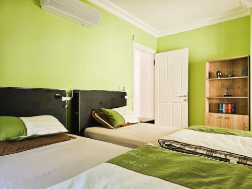 two beds in a room with green walls at Alanya Family Paradise Sea View in Alanya