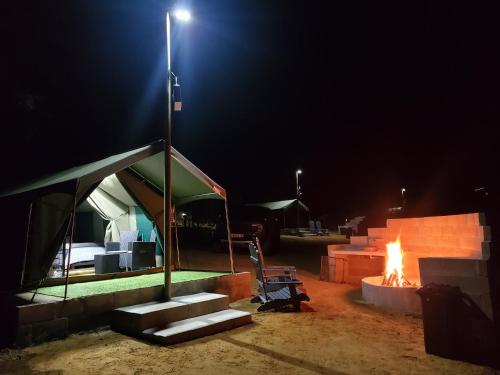 a tent with a fire in front of it at night at Peace Haven @ Windfarm Accommodation in Yzerfontein