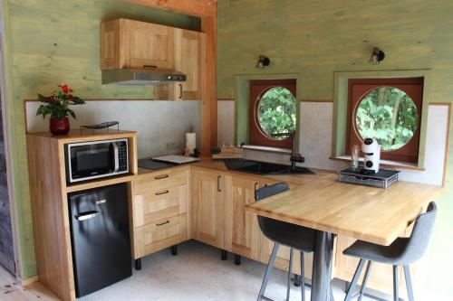 a kitchen with a wooden table and a black refrigerator at Entre mare et chêne in Frasnes-lez-Anvaing