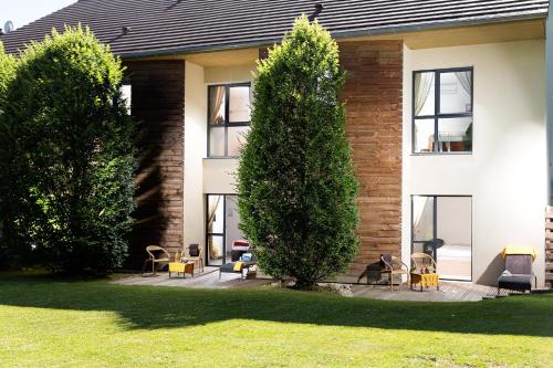 une maison avec des chaises et des arbres devant elle dans l'établissement Hôtel Auberge de Chavannes, à Courlans