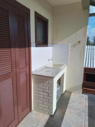 ein Bad mit einem Waschbecken neben einem Gebäude in der Unterkunft Apt com vista para o mar in Capão da Canoa