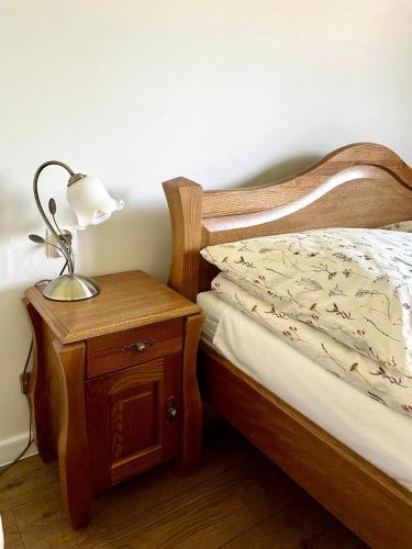 a bed with a nightstand with a lamp on it at Dobranocka Noclegi - blisko Energylandia in Spytkowice