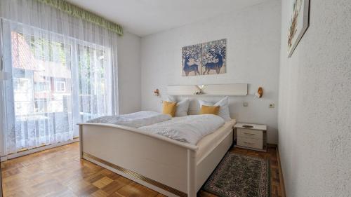 ein weißes Schlafzimmer mit einem Bett und einem Fenster in der Unterkunft Gästehaus Fehrenbacher Schweiz in Masserberg