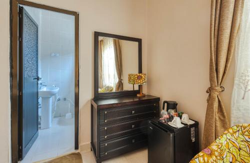 La salle de bains est pourvue d'un lavabo, d'un miroir et d'une commode. dans l'établissement Shivo Guest House, à Kiembi Samaki