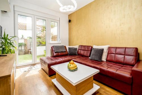 a living room with a red leather couch and a table at Apartment Urban Garden in Belgrade
