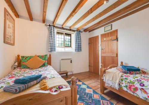 two beds in a room with wooden ceilings at 1 New Thatched Cottage in Edingthorpe