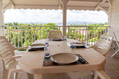 una mesa de madera con platos y vasos en el balcón en Location saisonnière bel appartement en Les Trois-Îlets