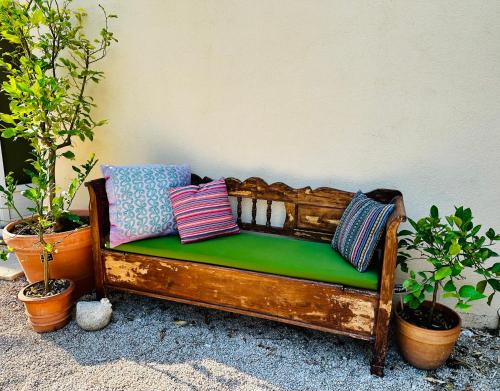 un banc en bois avec des oreillers à côté des plantes dans l'établissement B&B Les Têtes de Mules - Adults Only, à Gémenos