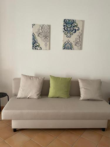 a couch with three pillows and two paintings on the wall at La Chiocciola - Casa vacanze in Erice