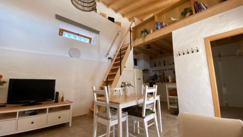 Habitación pequeña con mesa, TV y escalera. en Casa de Alcaria en Alcaria