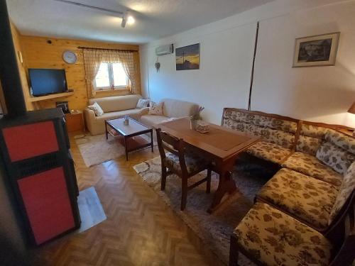 een woonkamer met een bank en een tafel bij Green cottage in Blidinje