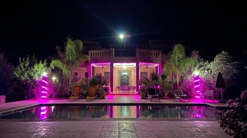 een huis met een zwembad in de nacht met paarse lichten bij Villa Chouiter Center in Marrakesh