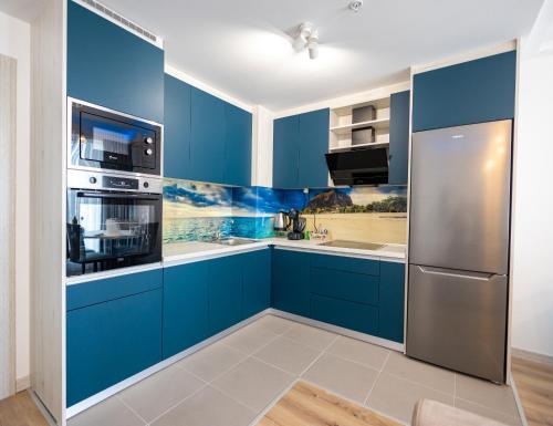 a kitchen with blue cabinets and stainless steel appliances at 16th Floor Sky View Condo With Pool And Fitness in Skopje