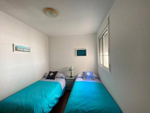 two blue beds in a room with a window at Apartamento en las salinas de Cabo de Gata in El Pozo del Cabo