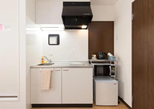cocina blanca con fregadero y microondas en Hotel Lucky, en Osaka