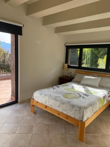 een slaapkamer met een bed en een groot raam bij Casa de camp Les Tretes in Les Preses