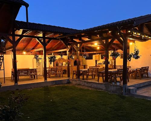 a wooden pavilion with tables and chairs in a yard at Pensiunea Andres in Sovata