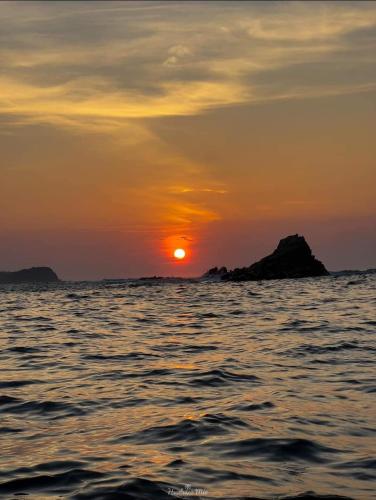 a sunset over the ocean with a rock in the water at Hotel Quinto Sol in Mazunte