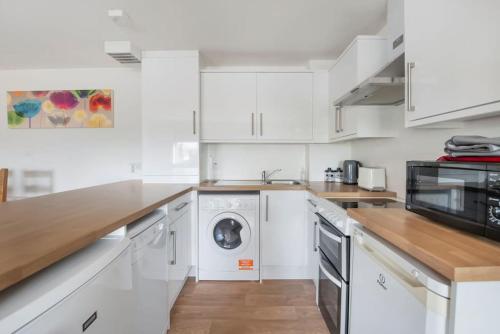 a kitchen with white cabinets and a washer and dryer at Wallace's Rest in Stirling
