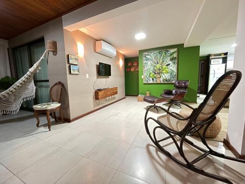 ein Wohnzimmer mit grünen Wänden und Schaukelstühlen in der Unterkunft FLAT MURO ALTO Manihi1101 in Porto De Galinhas
