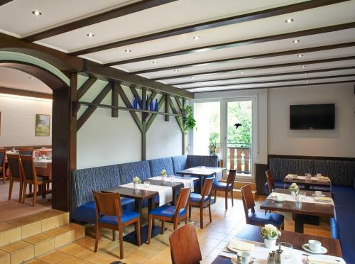 a restaurant with tables and chairs and a tv at Hotel Münster in Emmelshausen