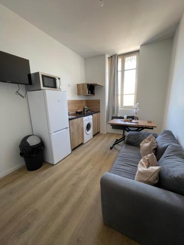 a living room with a couch and a kitchen at T1 Bohème - Terrasse - Proche du stade - 304 in Saint-Étienne