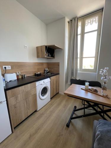 a kitchen with a washing machine and a table at T1 Bohème - Terrasse - Proche du stade - 304 in Saint-Étienne