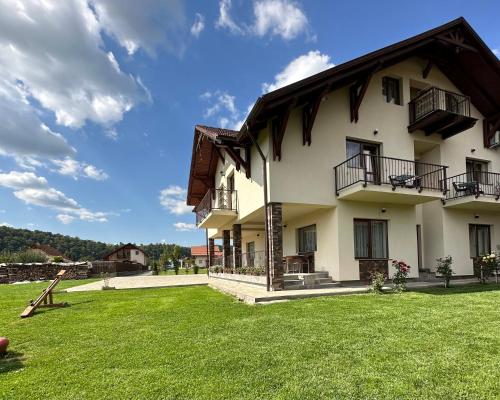 a large white house with a grass yard at Pensiunea Andres in Sovata