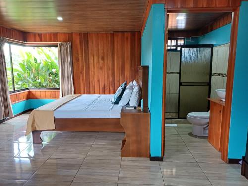 a bedroom with a bed and a bathroom with a toilet at Cabañas Sueños del Arenal in Fortuna