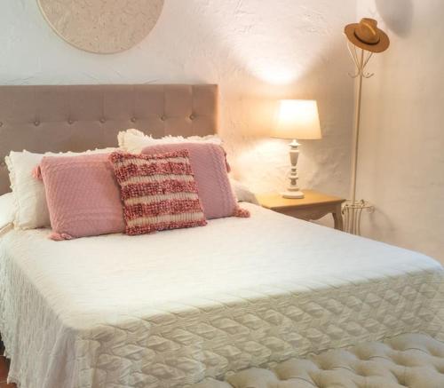 1 dormitorio con 1 cama grande con almohadas rosas y blancas en Ranchito de Alhucemas,piscina privada y barbacoa, en Montellano