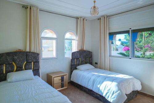 1 Schlafzimmer mit 2 Betten und 2 Fenstern in der Unterkunft Villa vue sur mer avec piscine in Tangier