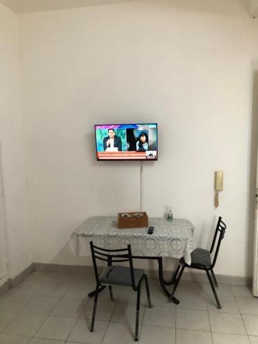 mesa con 2 sillas y TV en la pared en Monoambiente en Buenos Aires