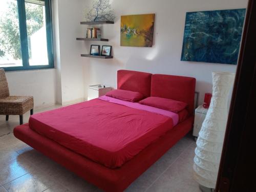 Cama roja en habitación con sofá rojo en camere Olmedo - 10 minuti da Alghero, en Olmedo