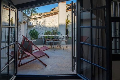 Cette chambre dispose d'une terrasse avec une fenêtre et une chaise. dans l'établissement MAISON LA TROPEZIENNE ... NEW • Fabulous 5* Luxe & Terrasse • 6P. Old Town, à Antibes