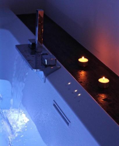 a bathtub with two candles and two lights on it at Nest House & Relax in Civitanova Marche