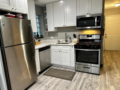 una cocina con electrodomésticos de acero inoxidable y armarios blancos en Cozy & Spacious in Irving Park, en Chicago