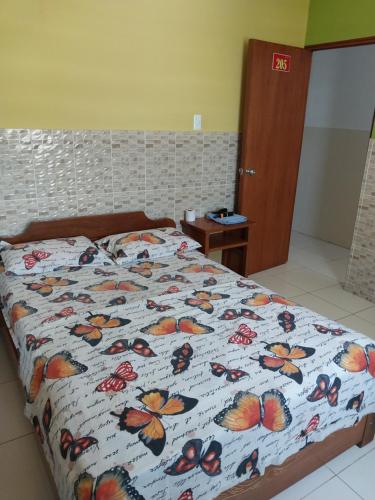 ein Bett mit einer Decke mit Schmetterlingen drauf in der Unterkunft Luz de Luna in Piura