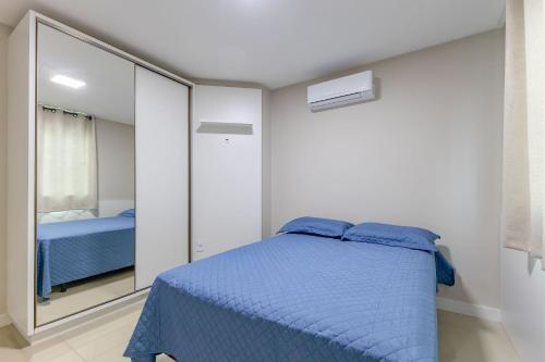 1 dormitorio con cama azul y espejo en Apartamento Com Piscina na Praia de Bombas - Apto 2 dorms para 6 pessoas, en Bombinhas