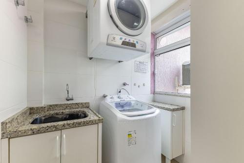una pequeña cocina con fregadero y lavadora en Apartamento Com Piscina na Praia de Bombas - Apto 2 dorms para 6 pessoas, en Bombinhas