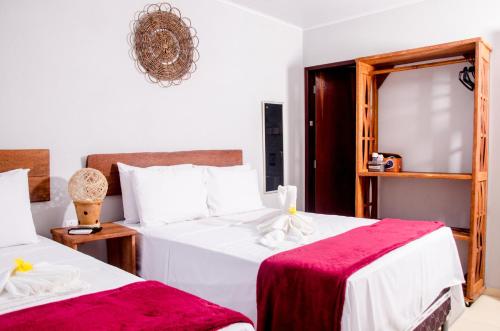 a bedroom with two beds and a mirror at Pousada Chalés do Toque in São Miguel dos Milagres