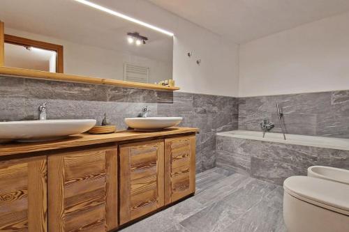 uma casa de banho com 2 lavatórios, um WC e uma banheira em Du Soleil vda la salle cir 93 em Remondey