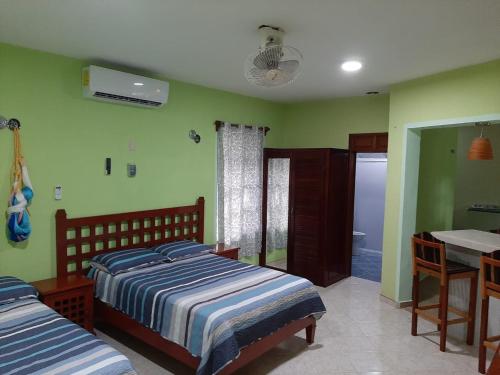 a bedroom with two beds and a table and a bathroom at Casa Caribe in Bacalar