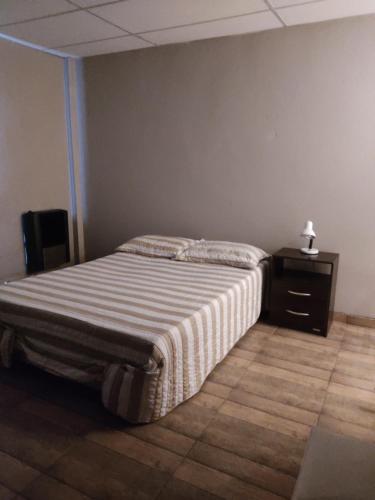 a bedroom with a bed and a night stand with a lamp at Apart Trelew in Trelew