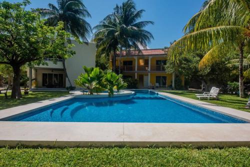 a swimming pool in front of a house with palm trees at Marysol private beach D12 next to nomads in Isla Mujeres