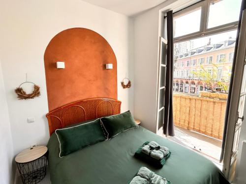- une chambre avec un lit vert et une grande fenêtre dans l'établissement Aux Arcades Mulhouse Hyper Centre, à Mulhouse