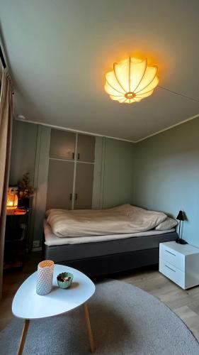 a room with a bed with a table and a light at Strøken liten leilighet i Svolvær. in Svolvær