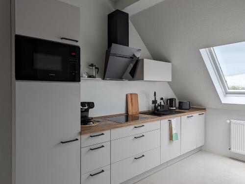 a kitchen with white cabinets and a microwave and a window at Vilipa-Apartments Nähe Red Bull Arena, Küche, Smart TV, Badewanne, Maisonette in Leipzig