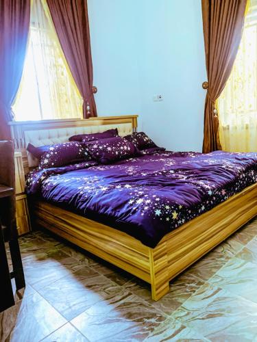 um quarto com uma cama com lençóis roxos e uma janela em Select Captivating Room with 1kingsized bed em Abuja