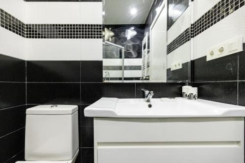 a bathroom with a sink and a toilet and a mirror at Cozy Apartment in Tbilisi City