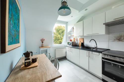 a kitchen with white cabinets and a wooden table at Family Apartment - Centrum in Kudowa-Zdrój